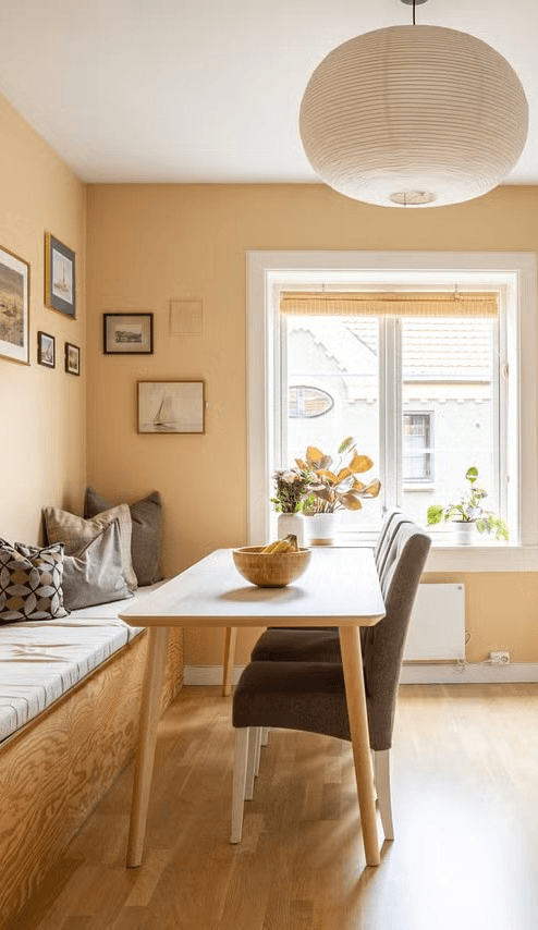 Spiseplass med varme gule vegger, trebenk og rund papirlampe